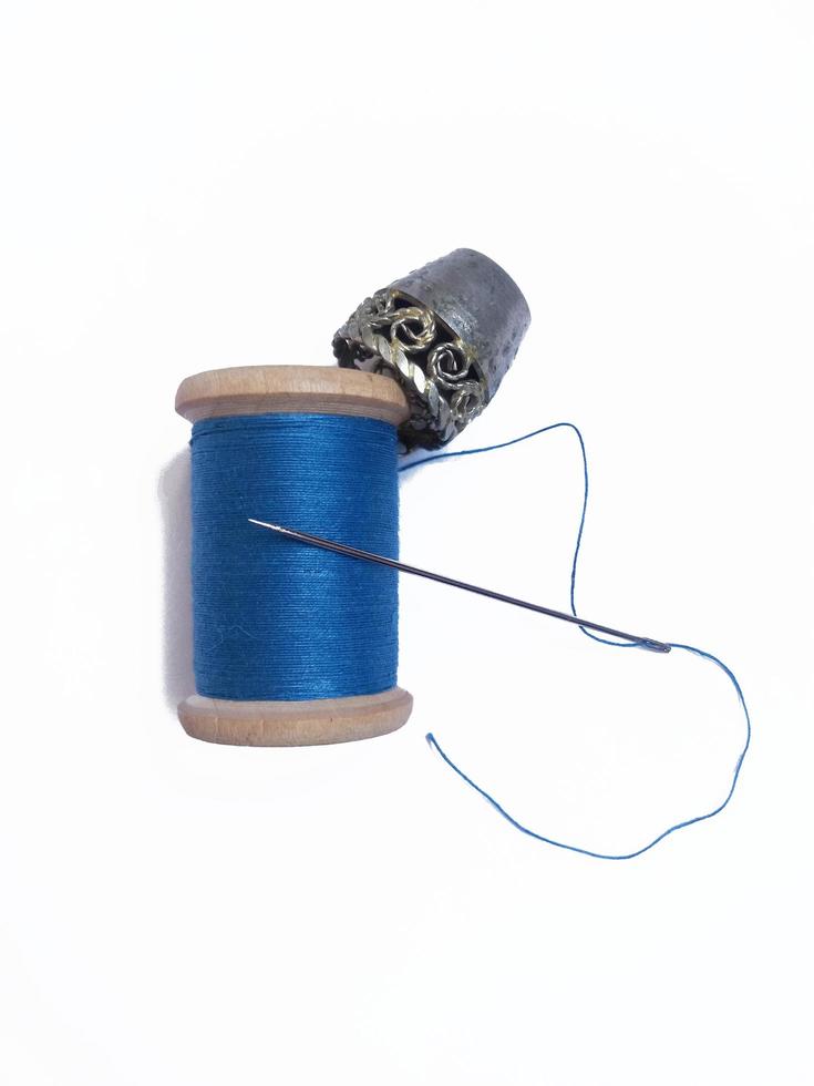 un' bobina di blu filo, ditale e ago foto