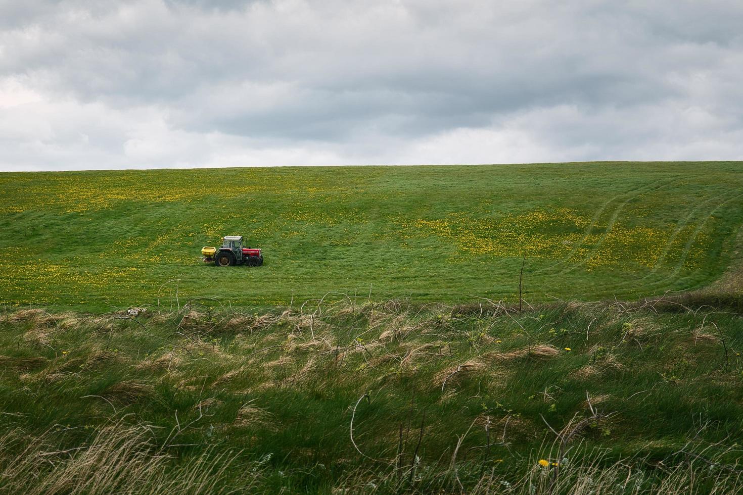 trattore guida su azienda agricola nel fiore campo di il silverstrand spiaggia nel Galway, Irlanda foto