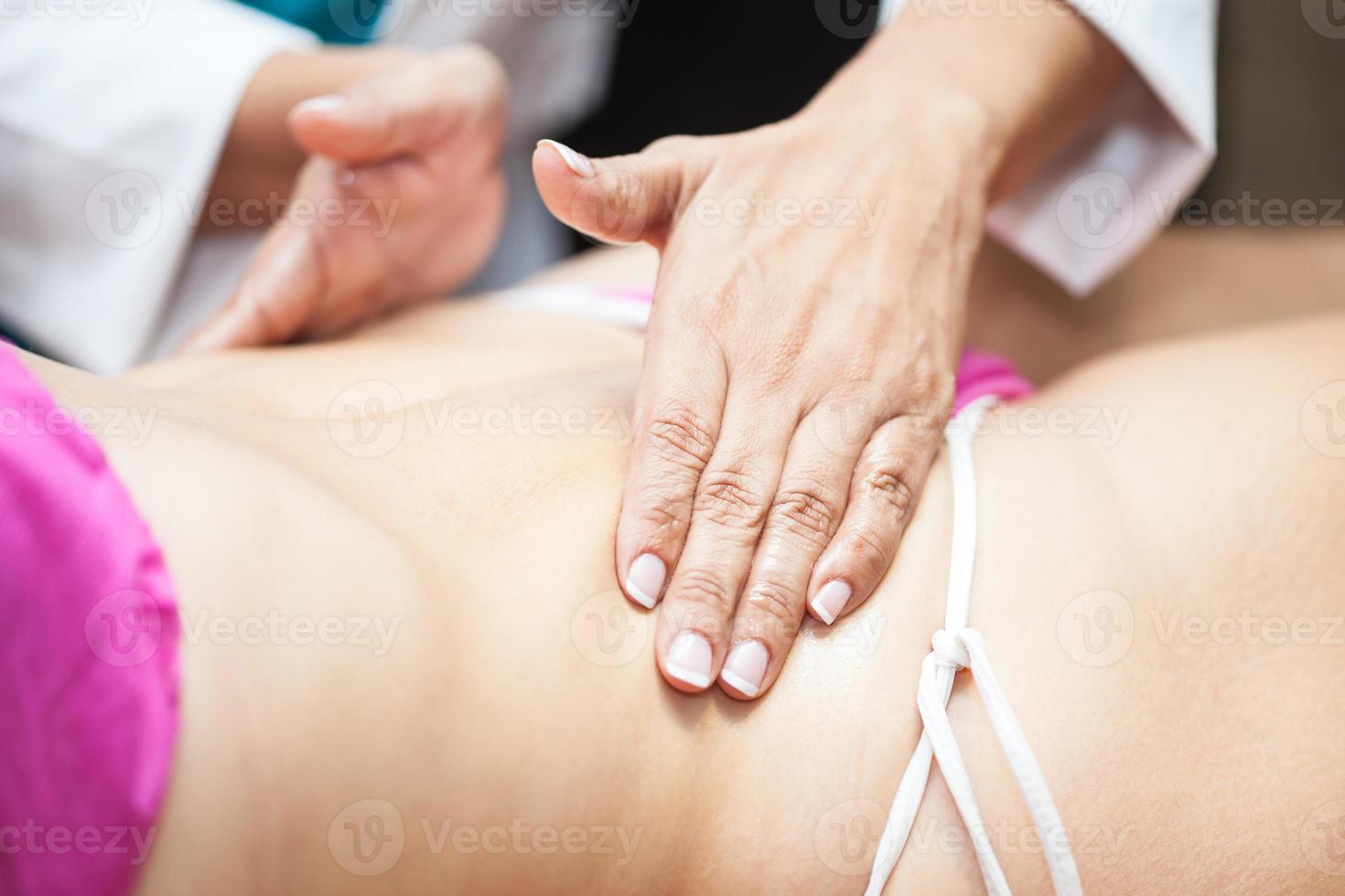 medico l'esecuzione un addominale massaggio su un' giovane femmina paziente foto