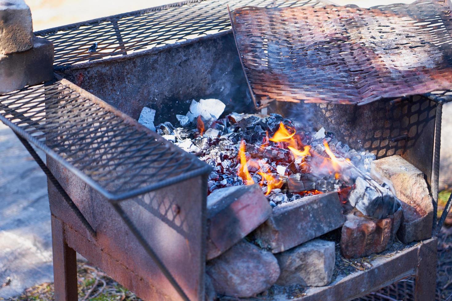 fuoco in una griglia vintage arrugginita all'aperto con sfondo sfocato foto