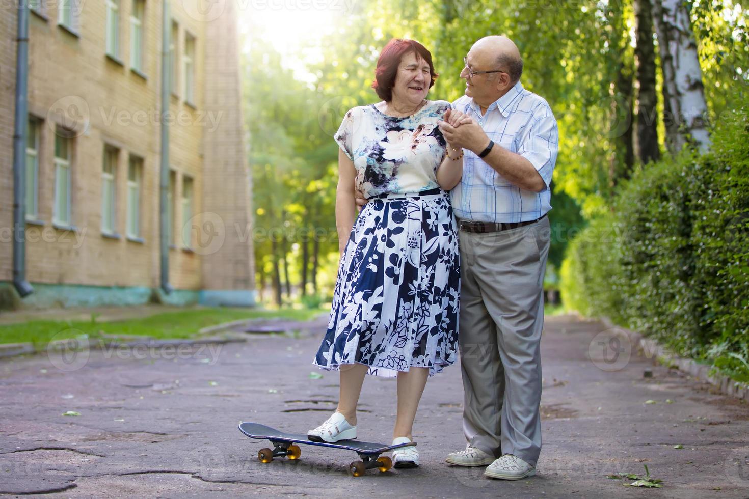 contento anziano coppia con un' skateboard. bello uomo e donna anziano cittadini. marito e moglie di vecchio età per un' camminare nel il città. foto