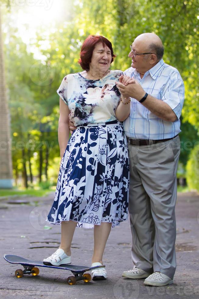 contento anziano coppia con un' skateboard. bello uomo e donna anziano cittadini. marito e moglie di vecchio età per un' camminare nel il città. foto