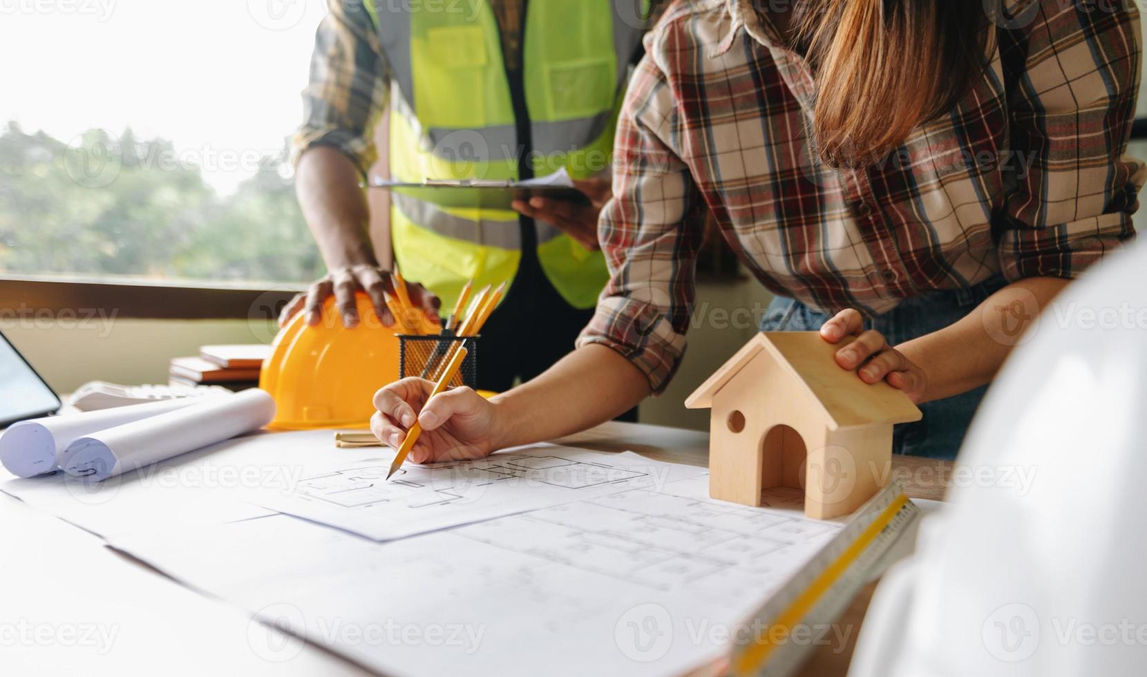 due colleghi che discutono di dati di lavoro e tablet, laptop con sul progetto architettonico in cantiere alla scrivania in ufficio foto