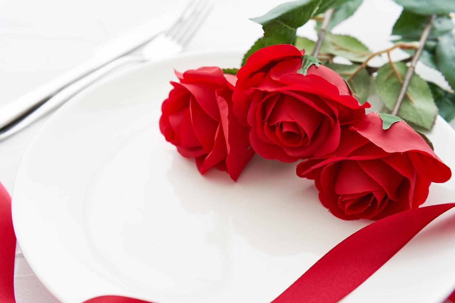 tavolo ambientazione San Valentino cena con rosso rosa su bianca piatto tavolo cibo sfondo. concetto di San Valentino cena cibo sfondo. San Valentino cena amore foto