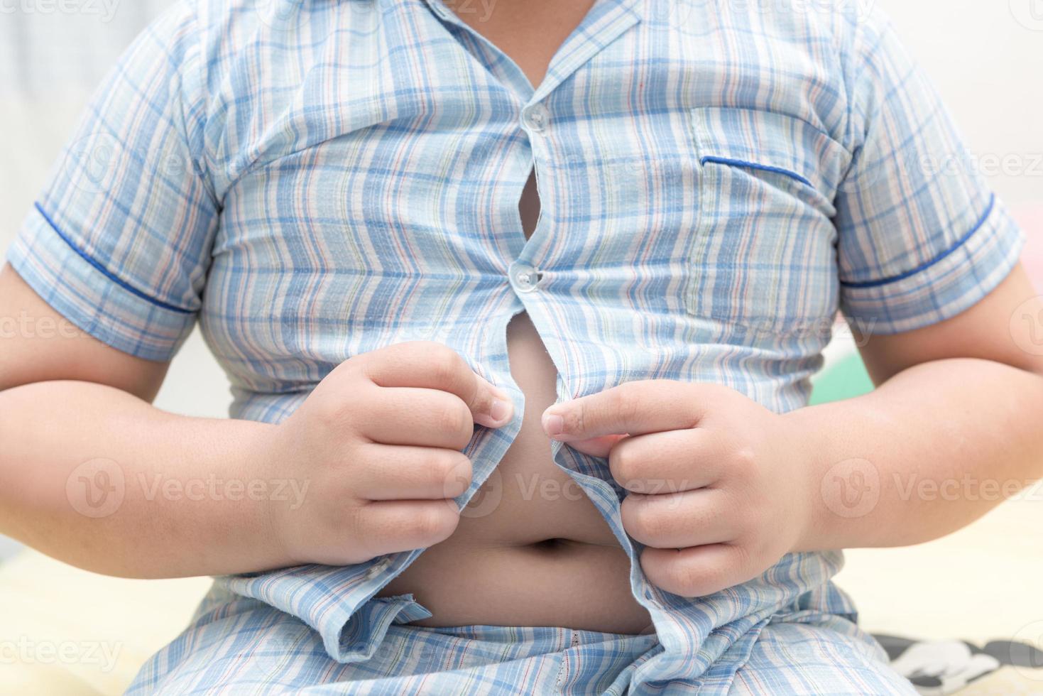 obeso Grasso ragazzo non posso pulsante su il suo camicia foto