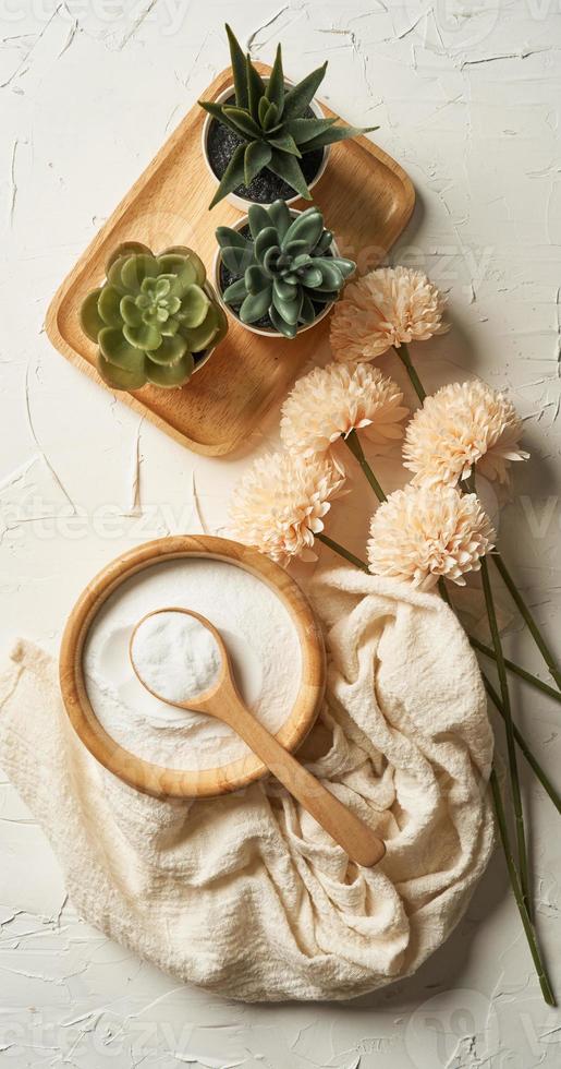 bellezza concetto di collagene polvere nel un' di legno ciotola e cucchiaio su bianca tavolo sfondo. Salute supplemento, proteina assunzione. fiore e verde pianta. superiore Visualizza o piatto posare foto