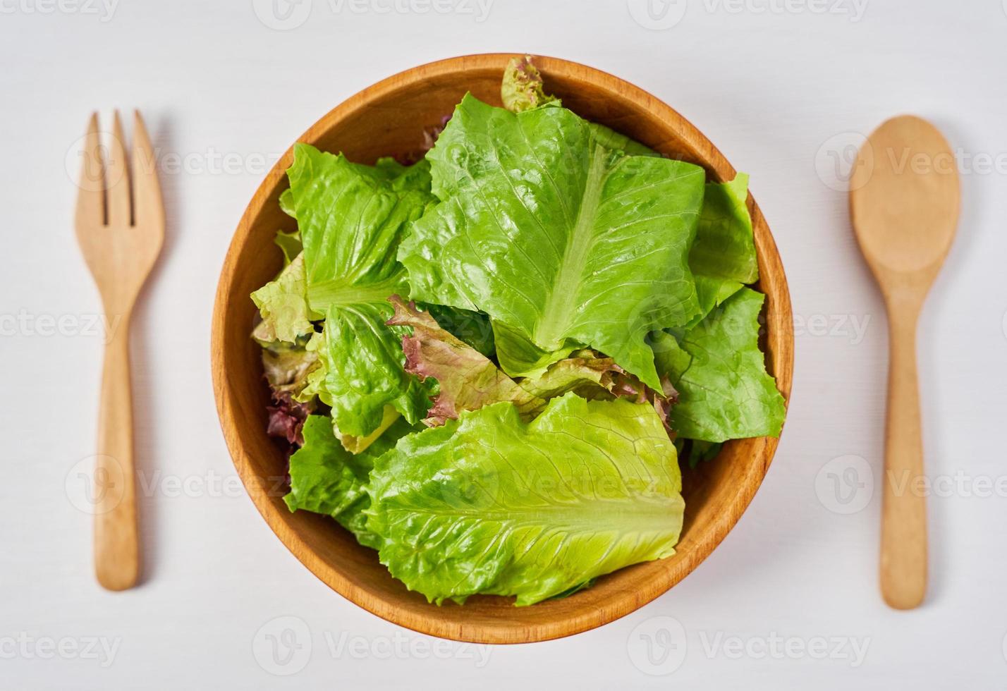 fresco insalata a partire dal verde le foglie nel un' di legno ciotola su bianca pulito umore sfondo con copia spazio. cucchiaio e forchetta foto