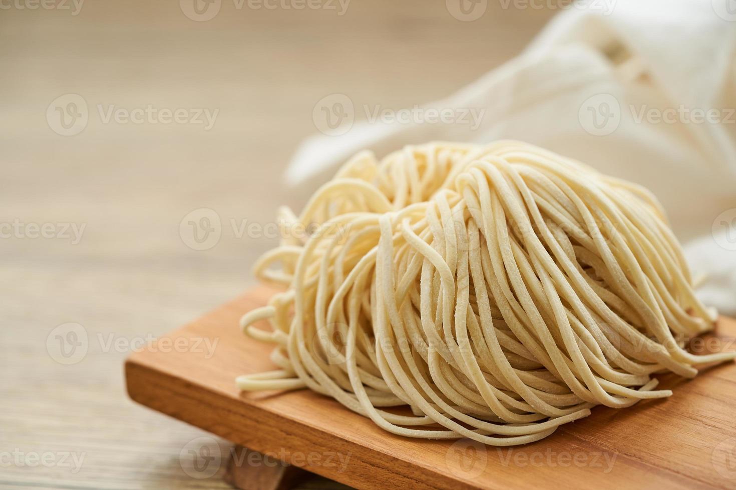 crudo ramen spaghetto nel legna piatto su di legno tavolo sfondo. fresco uovo ramen tagliatelle e di legno sfondo. foto