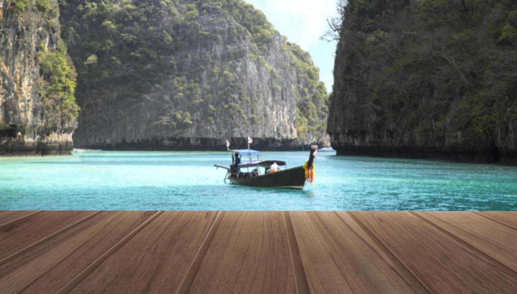 tavolo in legno sulla vista dall'alto del bellissimo mare e barca di legno con le montagne nella località tropicale durante una giornata estiva foto