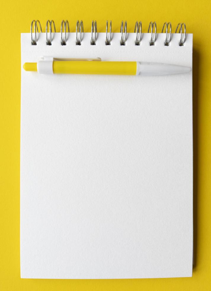 foglio bianco del taccuino con la penna su esso. concetto educativo nei colori giallo e bianco. fotografia stock. foto