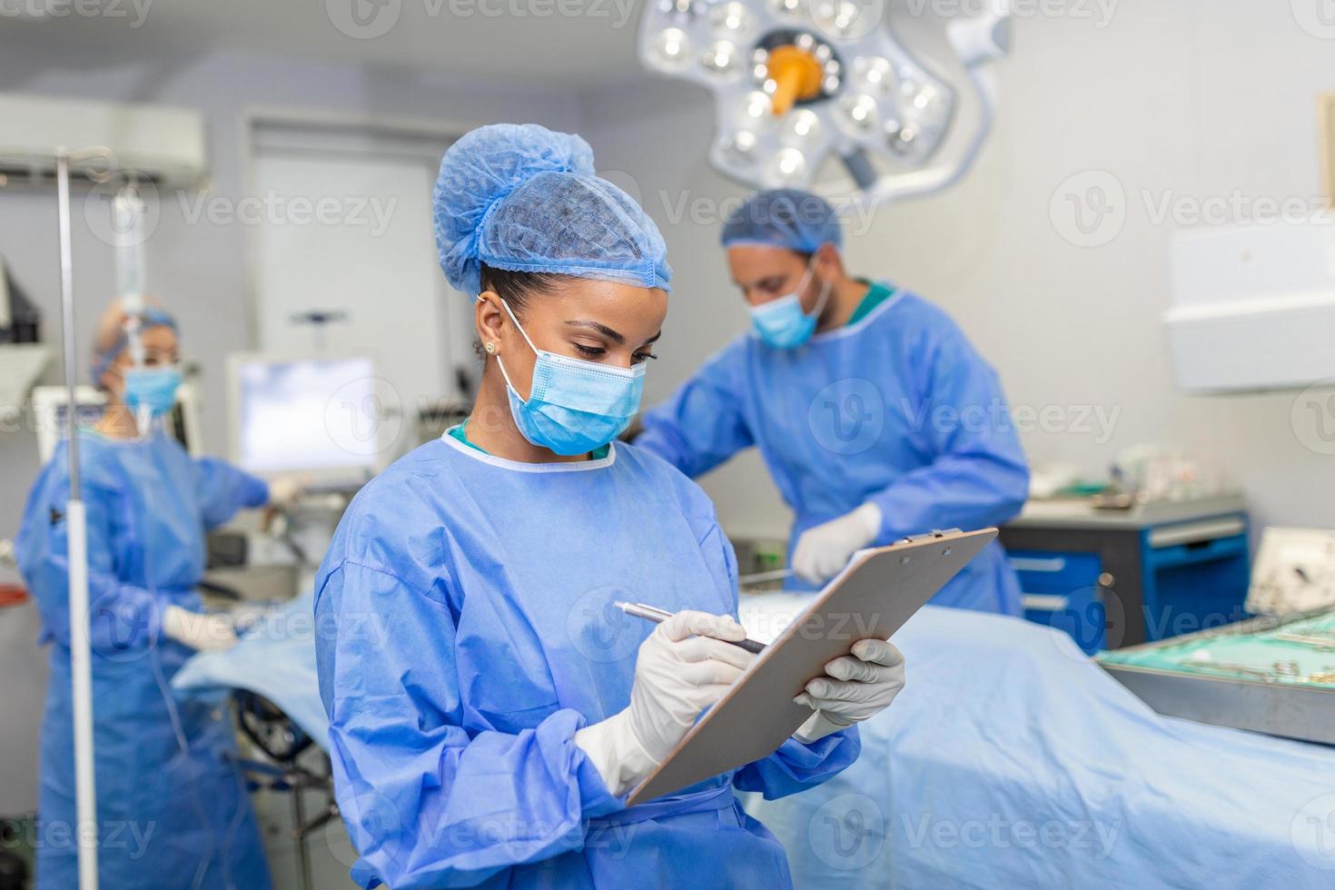 chirurgo scrittura su appunti nel operazione camera, anestesista scrittura il aggiornamenti foto
