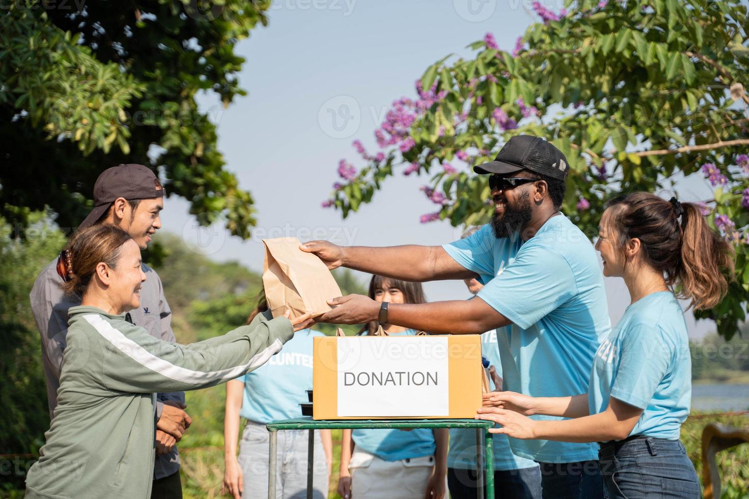 squadra di volontari Tenere donazioni scatole nel all'aperto. volontari mettendo cibo nel donazione scatole, sociale lavoratore fabbricazione Appunti beneficenza foto