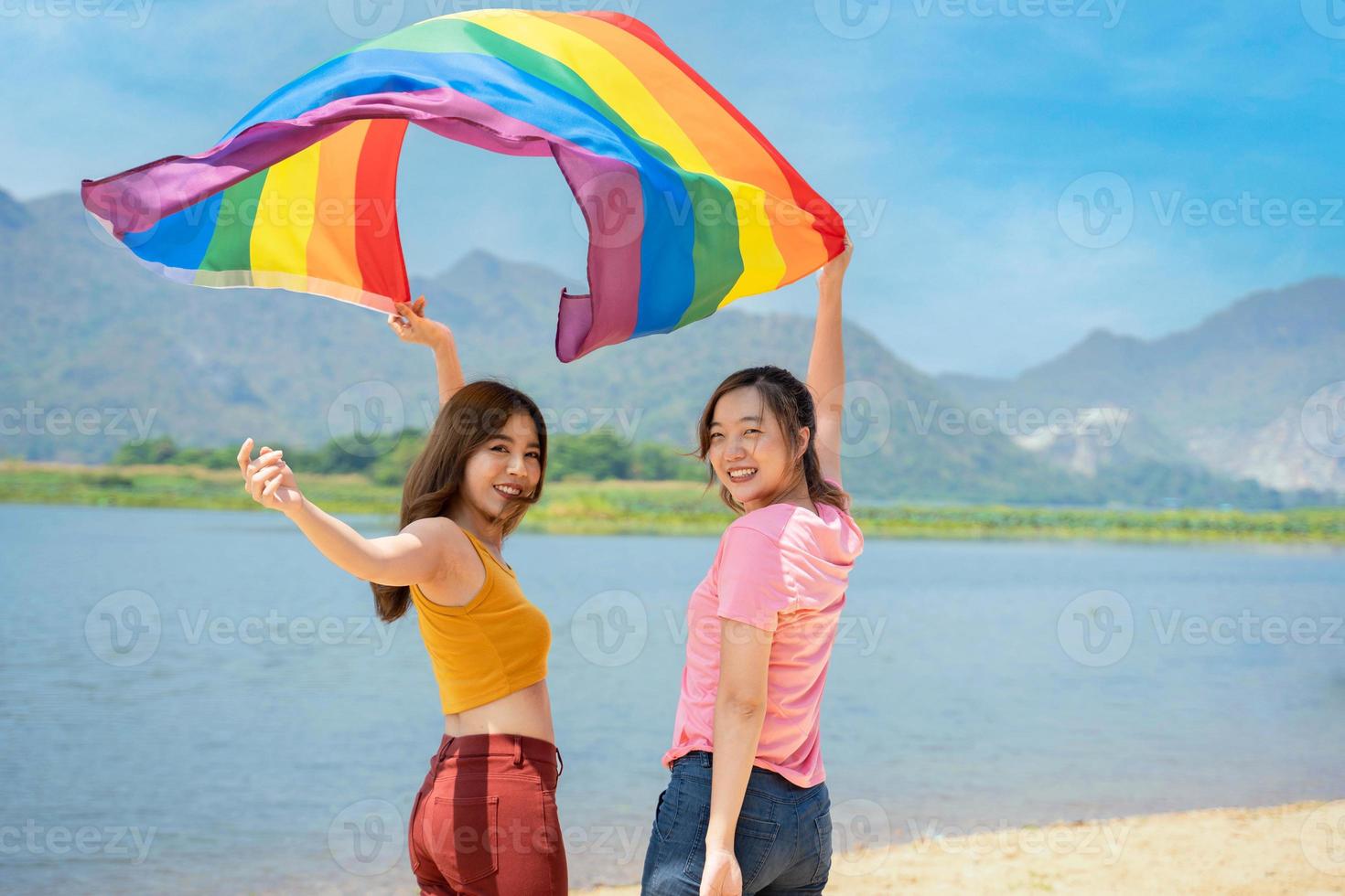 contento lesbica, bellissimo asiatico giovane Due donne, ragazza gay, coppia amore momento la spesa bene tempo insieme, Tenere o agitando lgbt arcobaleno, orgoglio bandiera insieme su il spiaggia. foto