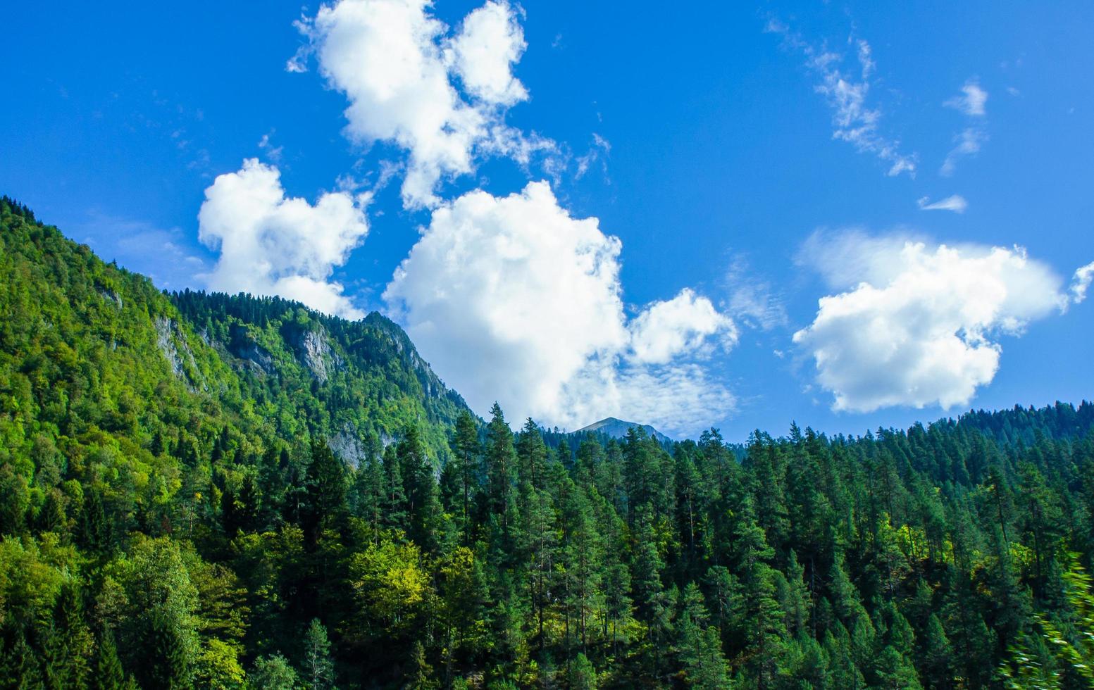 paesaggio con montagne e foreste con un cielo blu nuvoloso in abkhazia foto