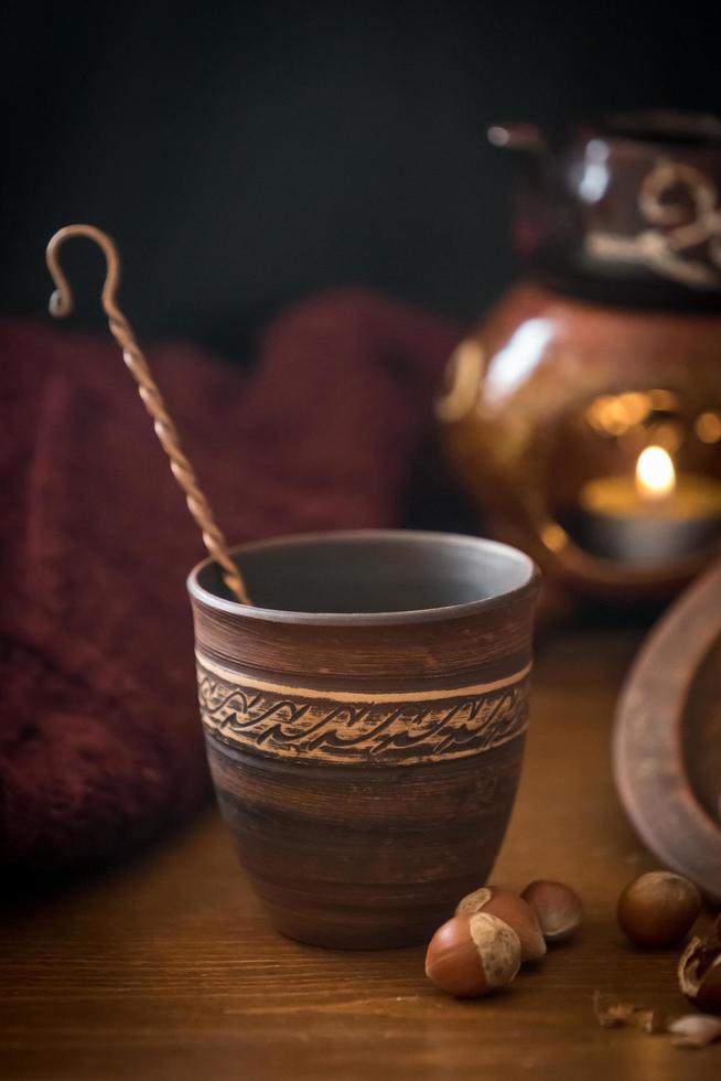 tazza di ceramica con un agitatore di metallo accanto ad alcune nocciole su un tavolo di legno foto