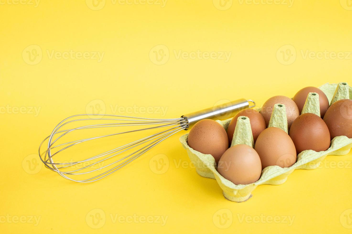 vassoio con pollo uova e un' metallo frusta su un' giallo sfondo. preparare ingredienti per cucinando foto