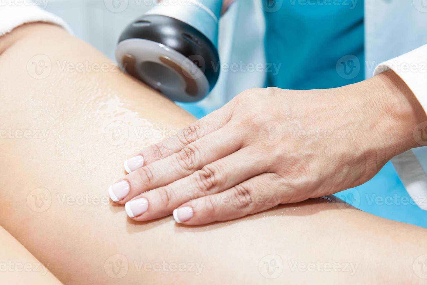 medico l'esecuzione un ultracavitazione trattamento su un' giovane femmina paziente gamba foto