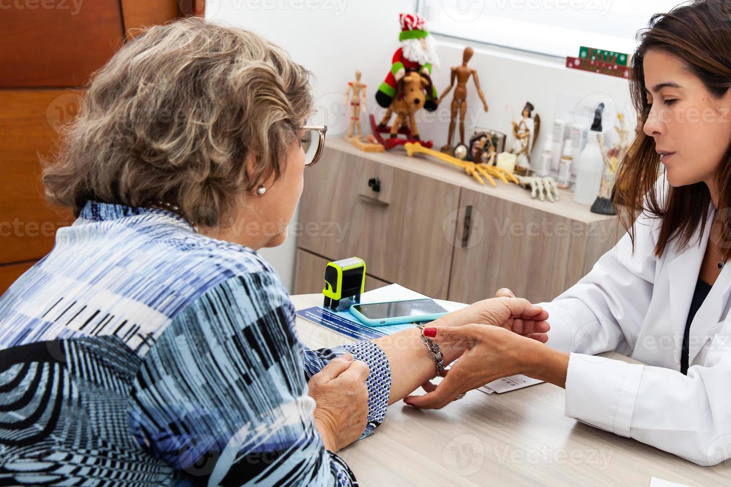 traumatologo femmina medico a sua ufficio l'esame un' anziano femmina paziente. scheletro osso malattia esame e medico aiuto. carriera concetto. foto