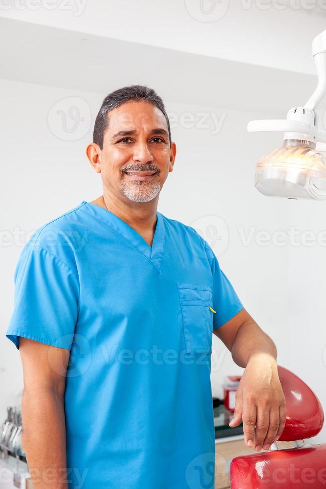 ritratto di un' maschio mezzo -invecchiato dentista a il suo ufficio foto