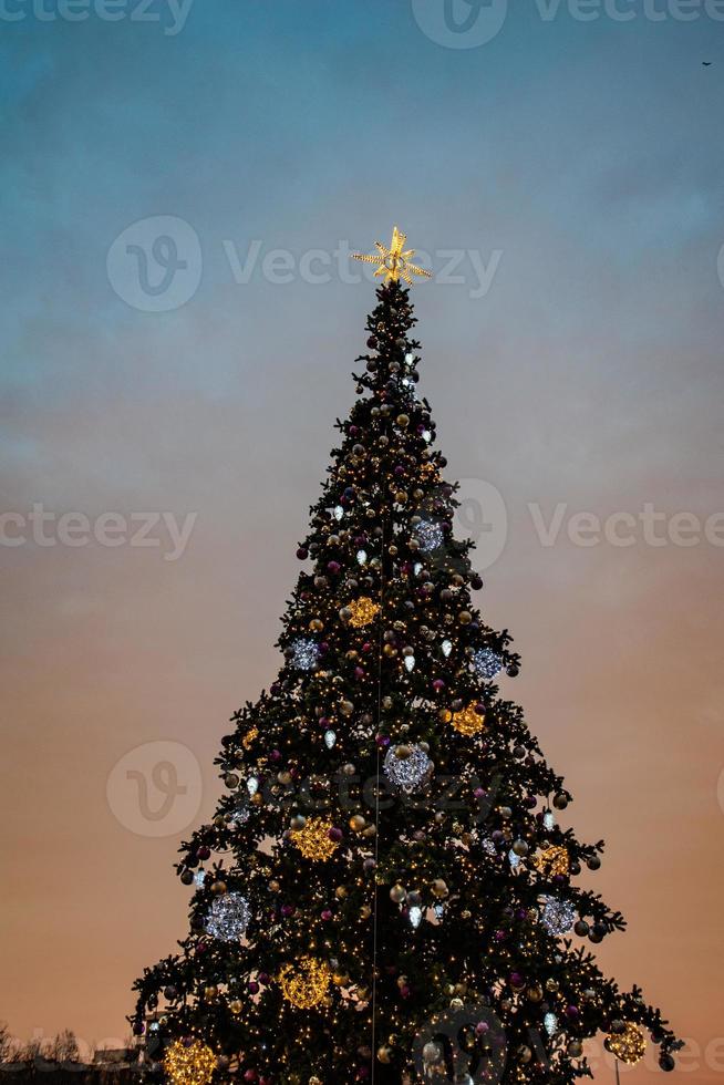 colorato Natale albero scintillante contro il sfondo di il sera pastello cielo foto