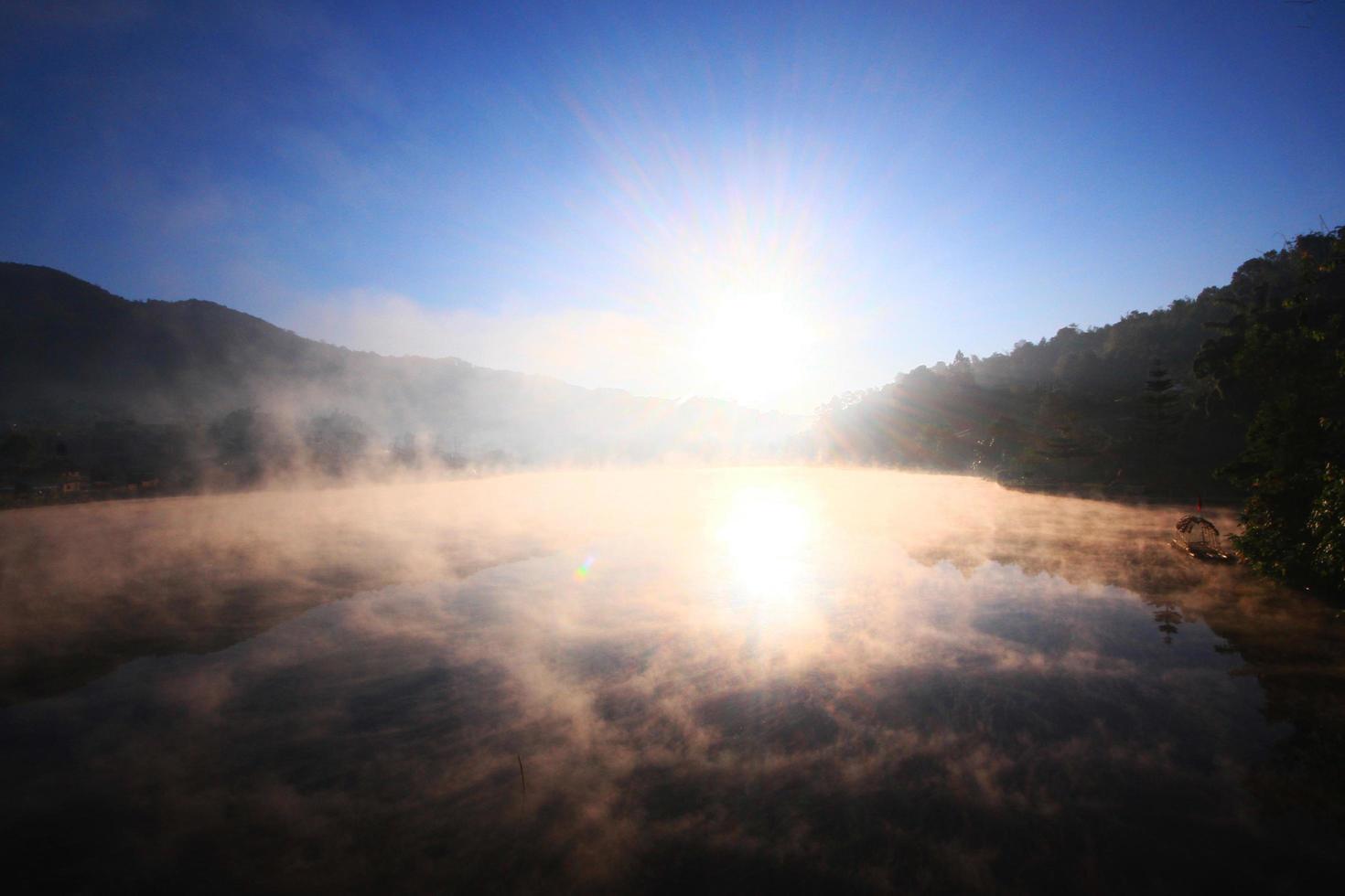 bellissimo paesaggio Paradiso di nebbia e nebbia al di sopra di il lago e Alba splendente con blu cielo riflessione su il acqua superficie a collina tribù villaggio su montagna nel Tailandia foto
