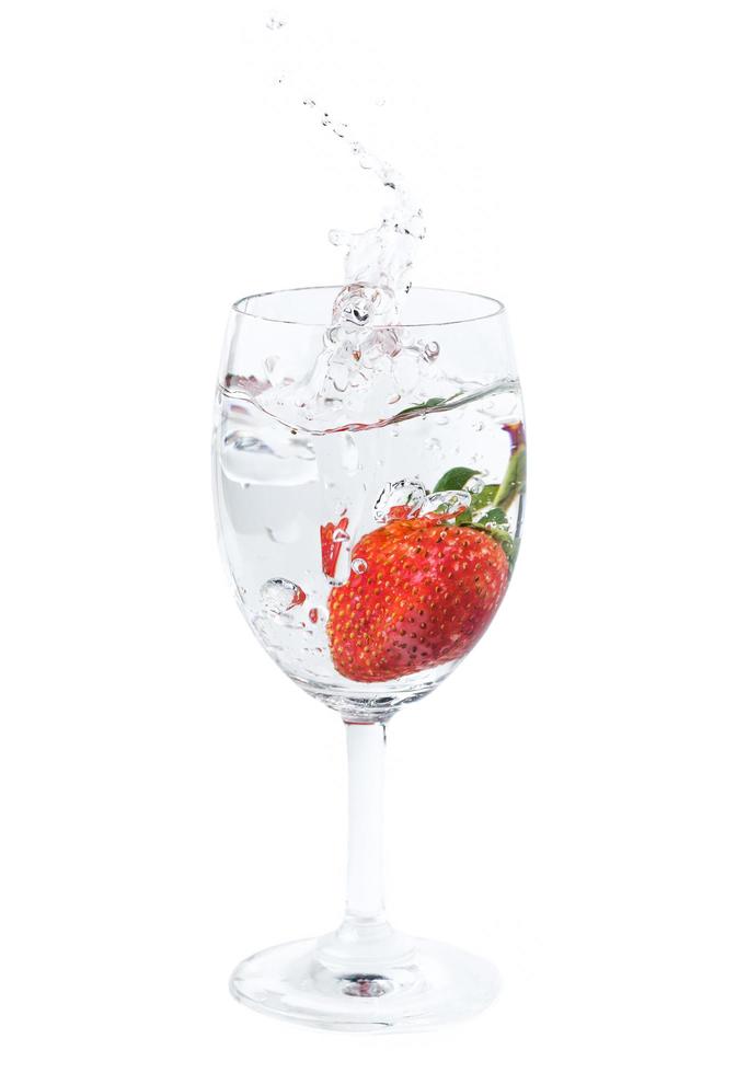 fresco fragola caduto in acqua nel vino bicchiere con spruzzo foto