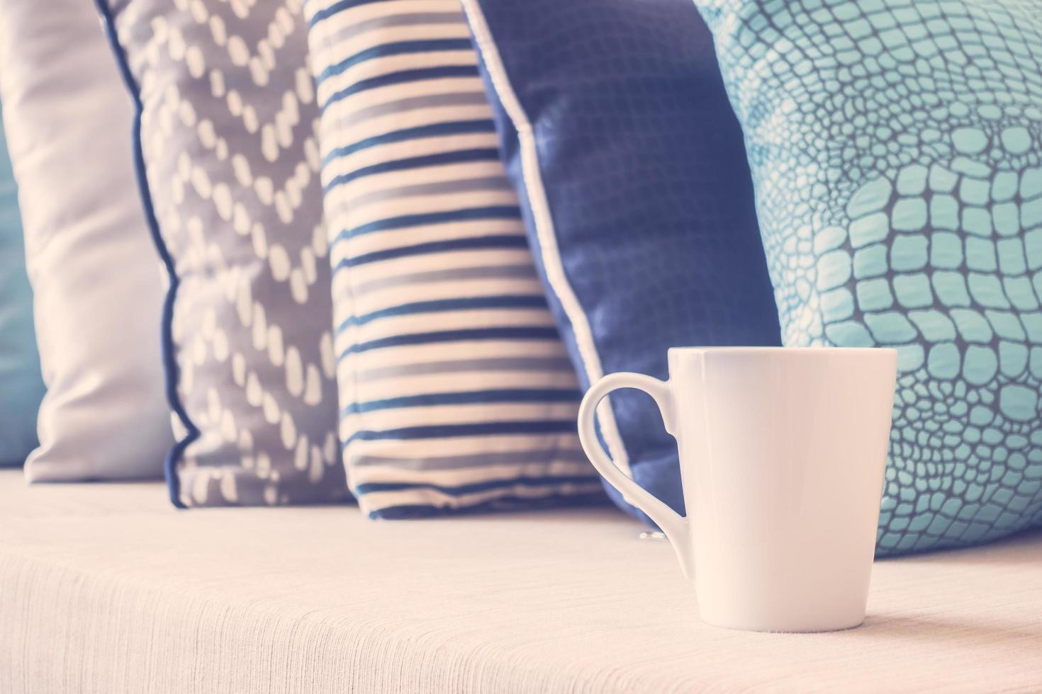 tazza di caffè bianco sul divano con decorazione cuscino foto