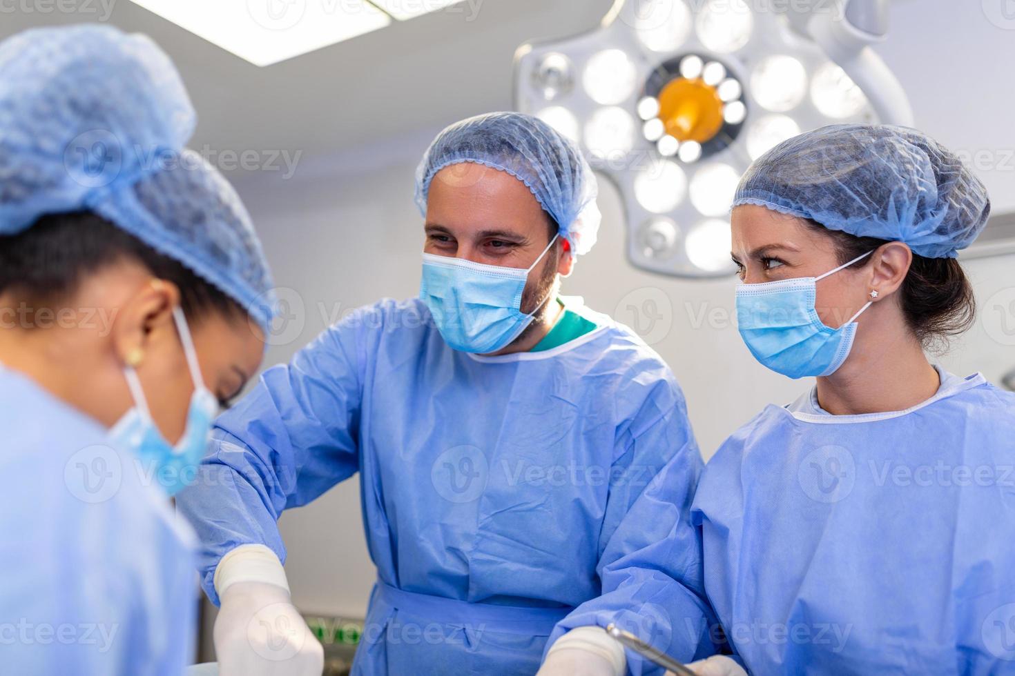 ritratto di squadra di multietnico chirurghi a opera nel un' operazione Teatro. parecchi medici circostante paziente su operazione tavolo durante loro opera. squadra chirurghi a opera nel operativo camera. foto