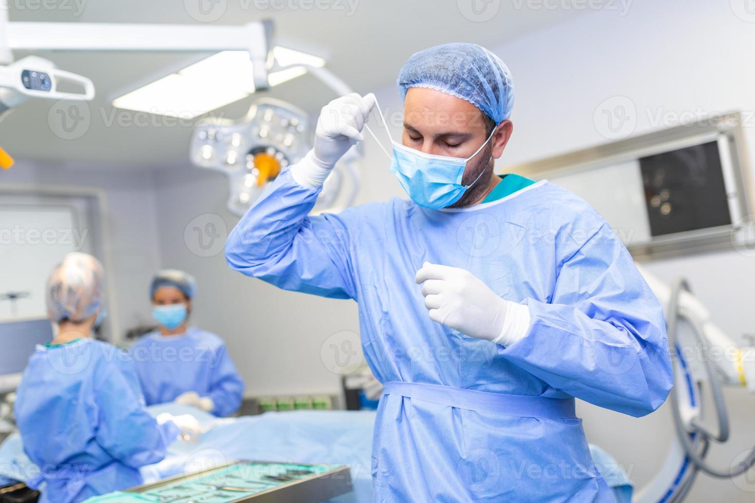 ritratto di maschio medico chirurgo assunzione via medico maschera in piedi nel operazione camera. chirurgo a moderno operativo camera foto