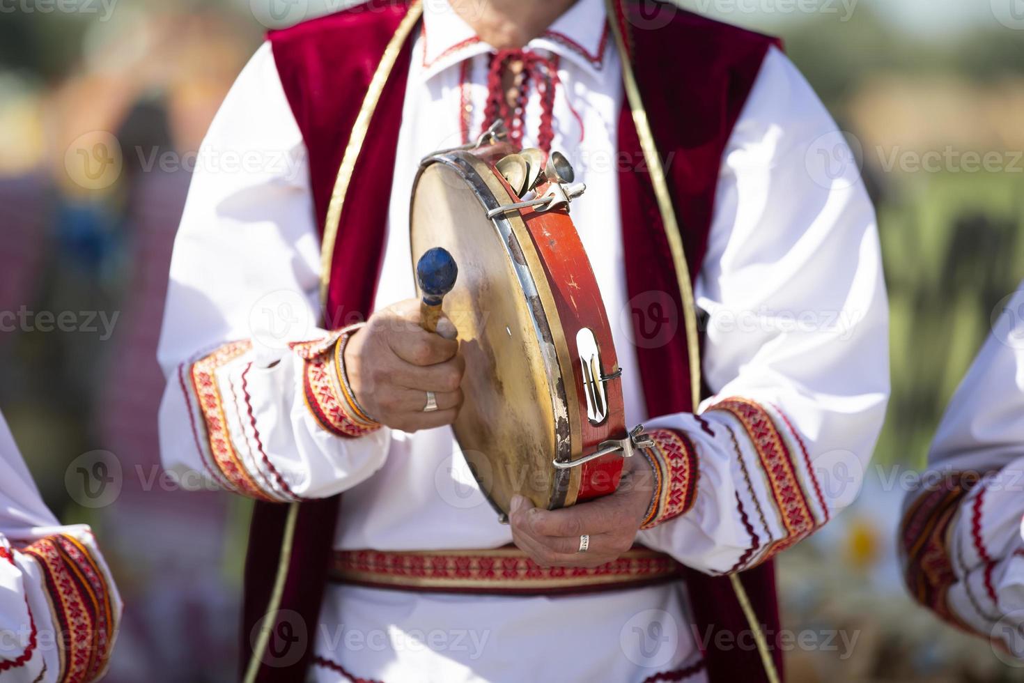 un' musicista nel ricamo giochi un etnico tamburellare. foto