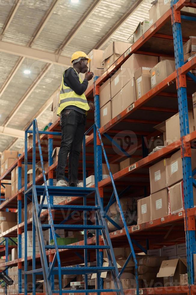 magazzino lavoratori nel un' grande magazzino scalata il scala per ispezionare il merce su il superiore scaffali. foto