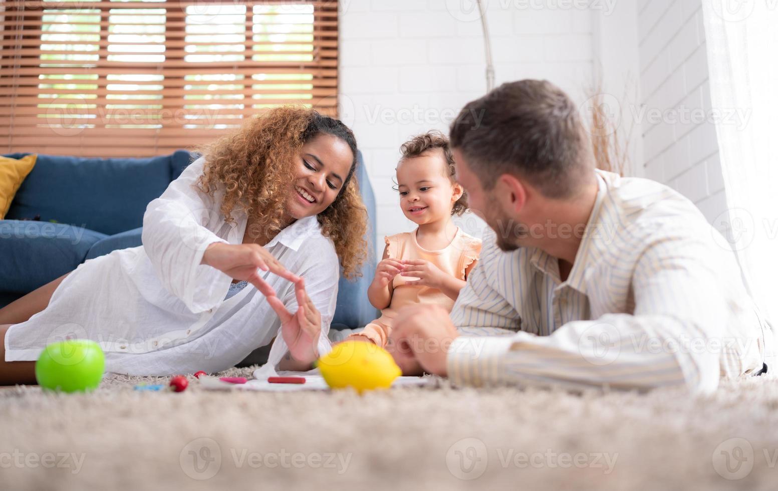 genitori e bambini rilassare nel il vivente camera di il Casa. orologio bambino dipingere su il carta felicemente. foto