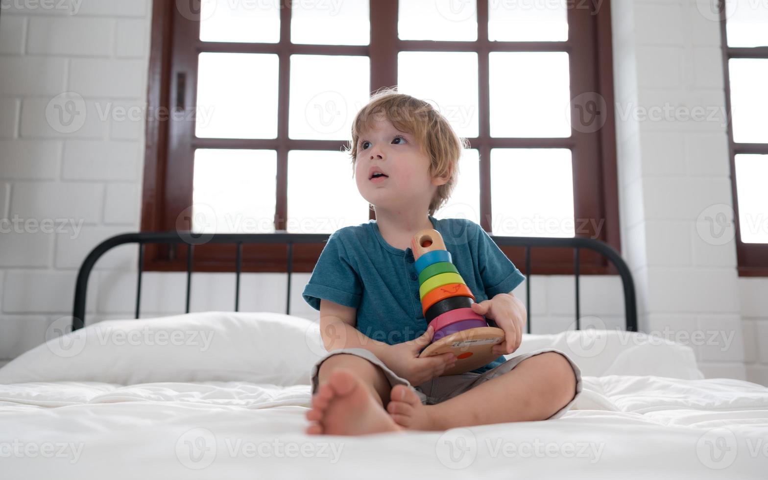 poco ragazzo nel il suo Camera da letto con un' nuovo giocattolo acquistato di il suo genitori per Aiuto lui Ottimizzare il suo pensiero abilità. foto