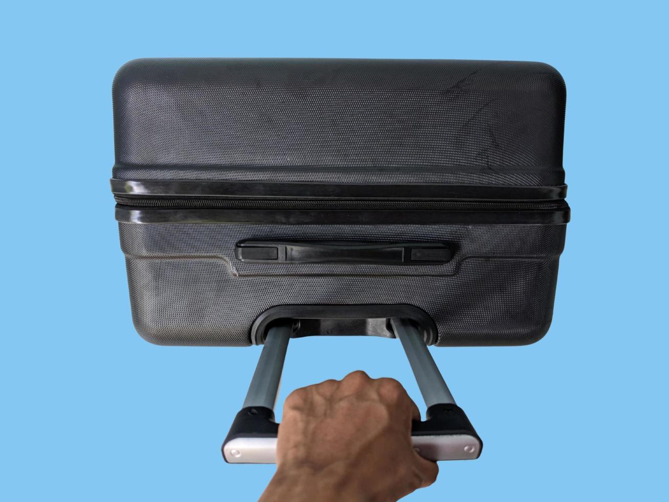 superiore Visualizza di mano Tenere valigia isolato su blu sfondo foto