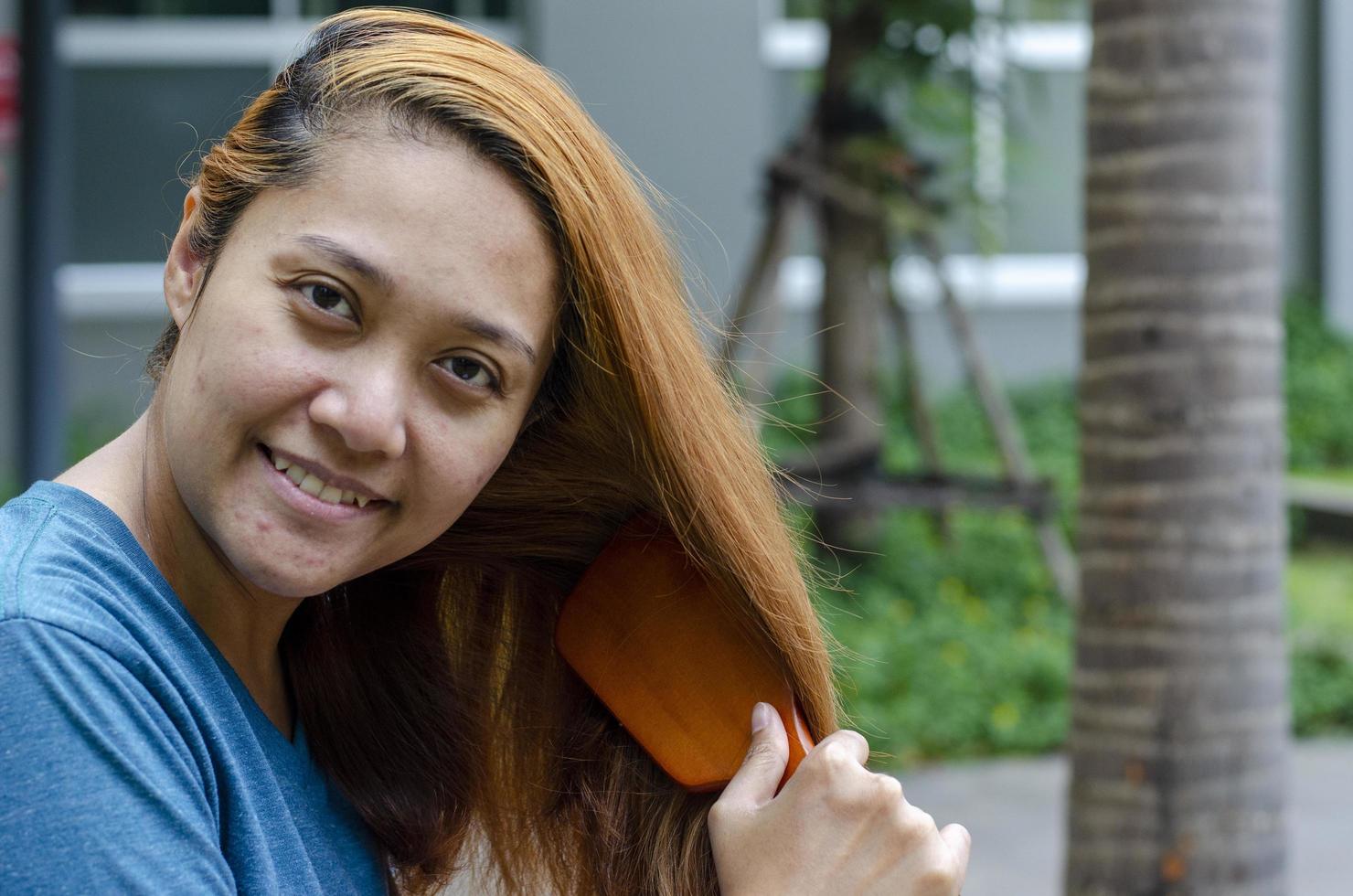 bionda dai capelli asiatico donna in posa pettinatura sua capelli con copia spazio foto