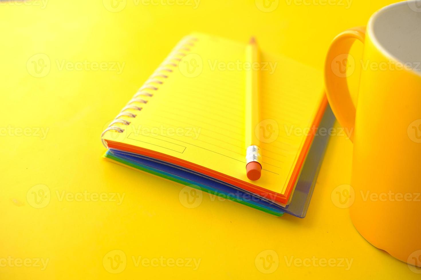 blocco note giallo con matita e tazza foto