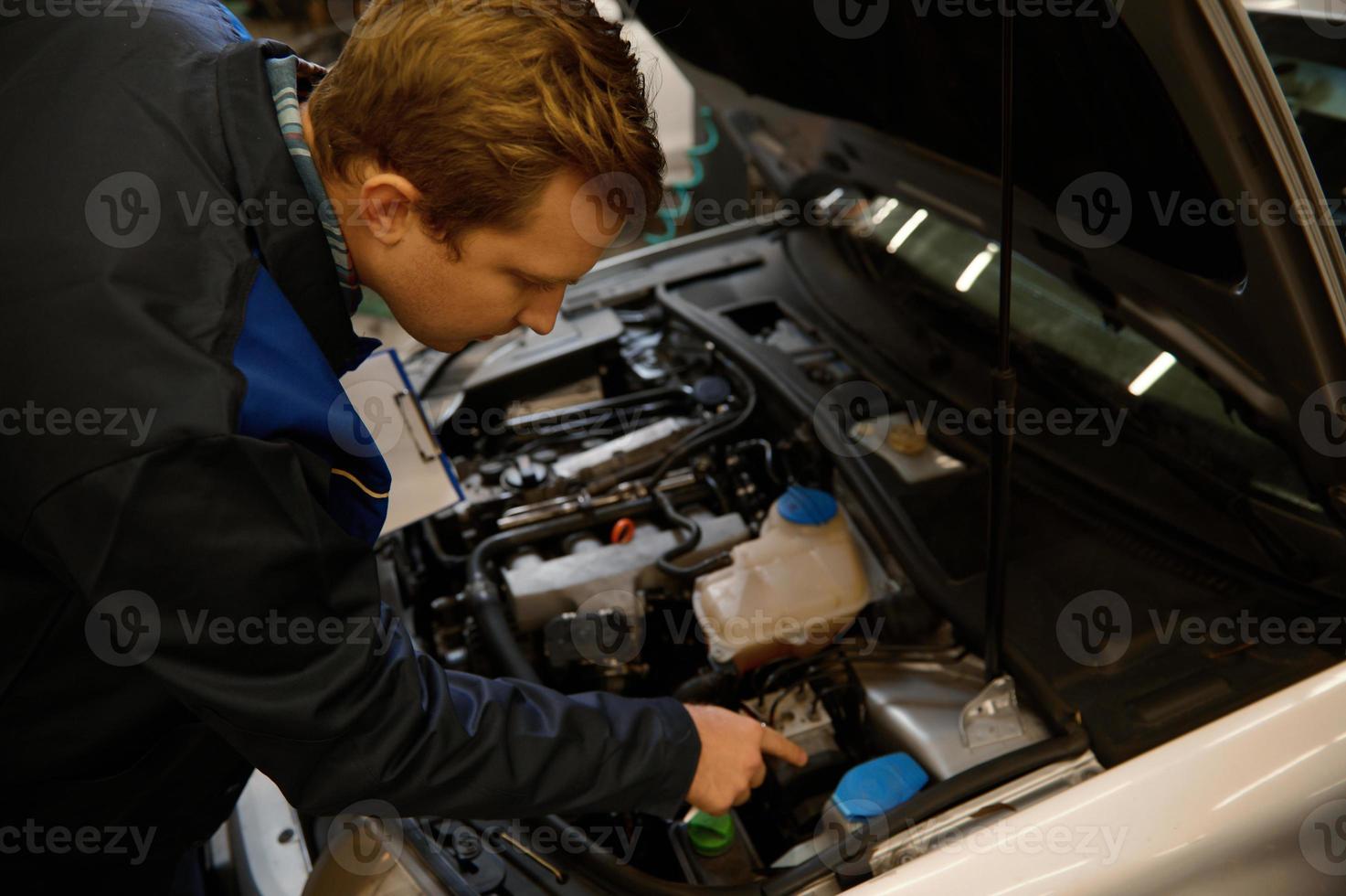 alto Visualizza di un' meccanico ispezionando il auto sotto cappuccio, l'esame il motore nel un' auto riparazione laboratorio . avvicinamento foto