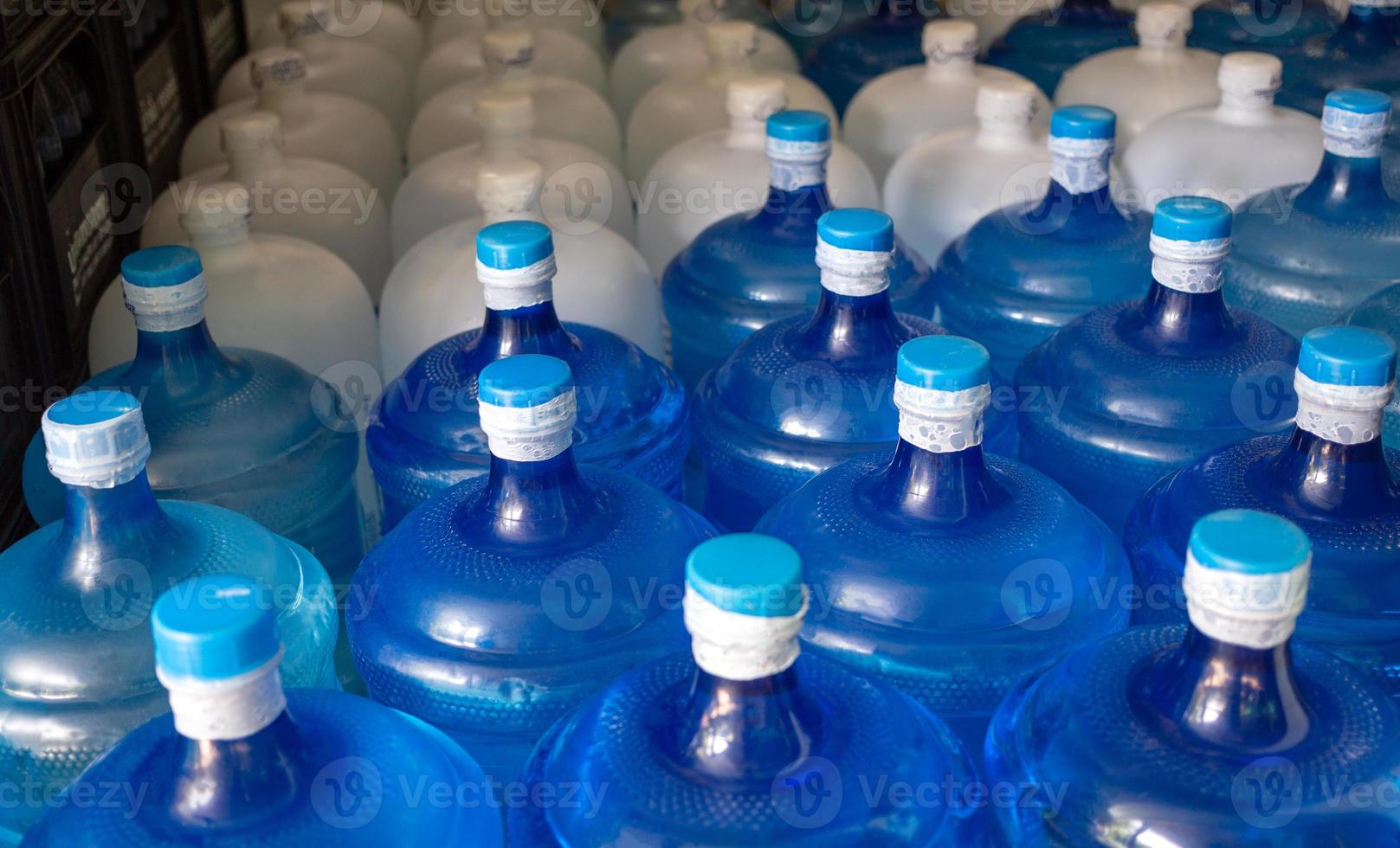 il blu acqua gallone e bianca gallone contenente potabile acqua avere stato sigillato con un' plastica foca nel il potabile acqua pianta per aspettare per consegna foto