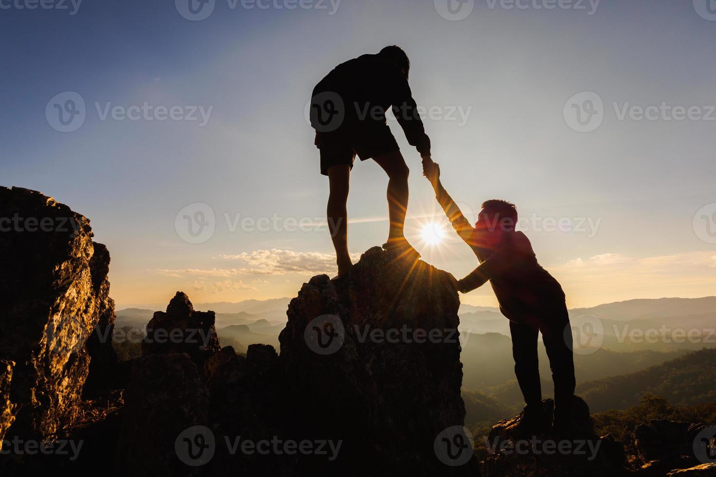 silhouette di il uomini porzione Tirare persone su a partire dal alto scogliere. foto