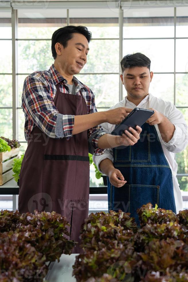 asiatico fruttivendolo e lavoratore utilizzando tecnologia per organizzazione vendita fresco biologico verde lattuga su Locale mercato foto