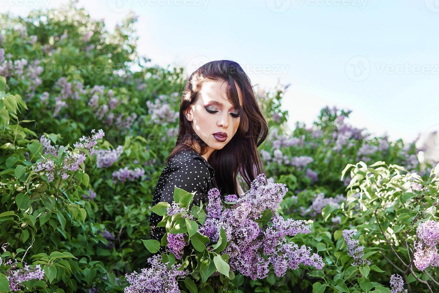 un' alla moda ragazza con buio capelli, un' primavera ritratto nel lilla toni nel estate. luminosa professionale trucco. foto