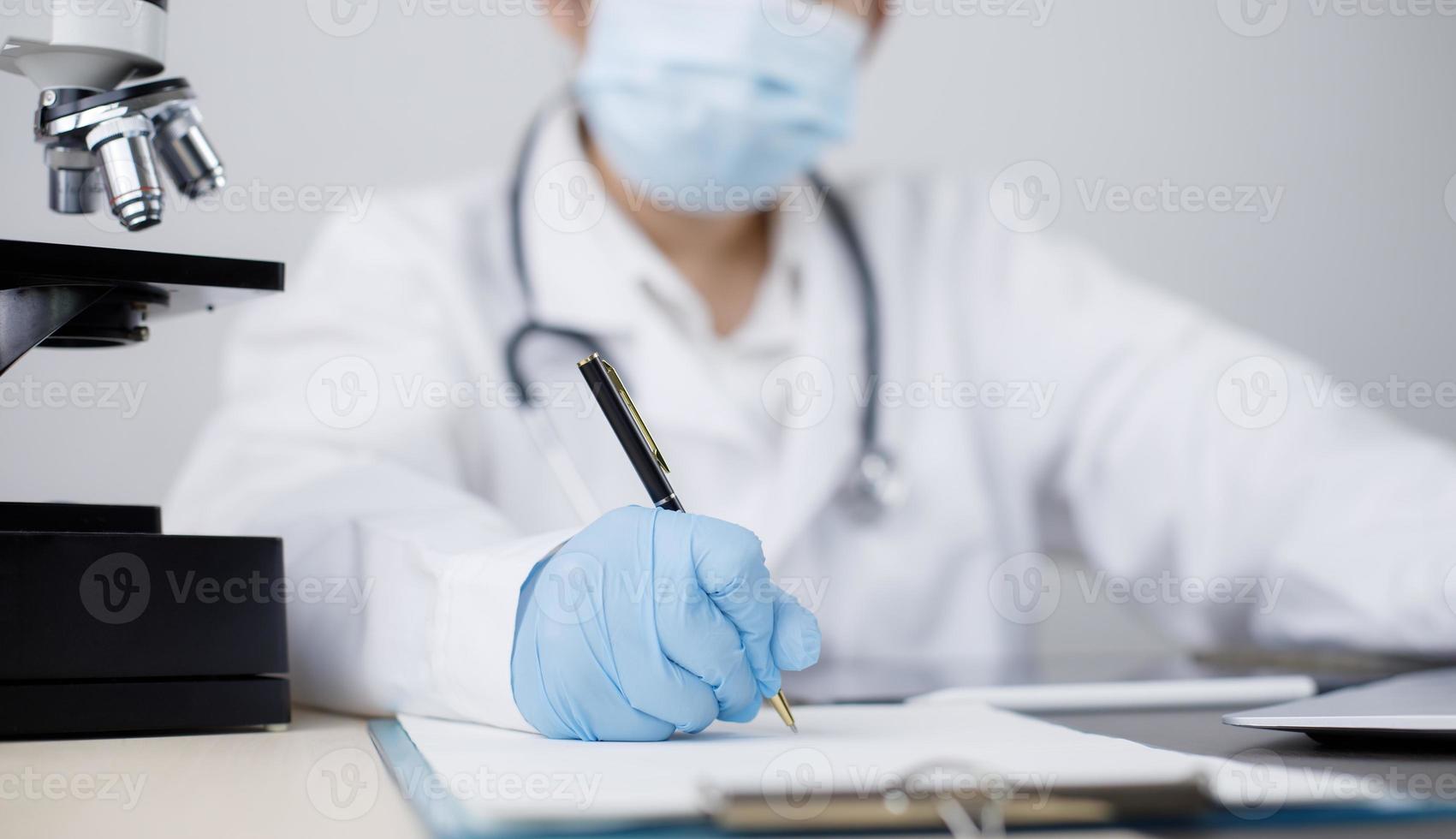 femmina medico seduta a scrivania e scrittura un' prescrizione sua paziente, prescrizione o firma medico rapporto o medico certificato o Salute verifica modulo documenti nel uffici o cliniche o ospedali foto
