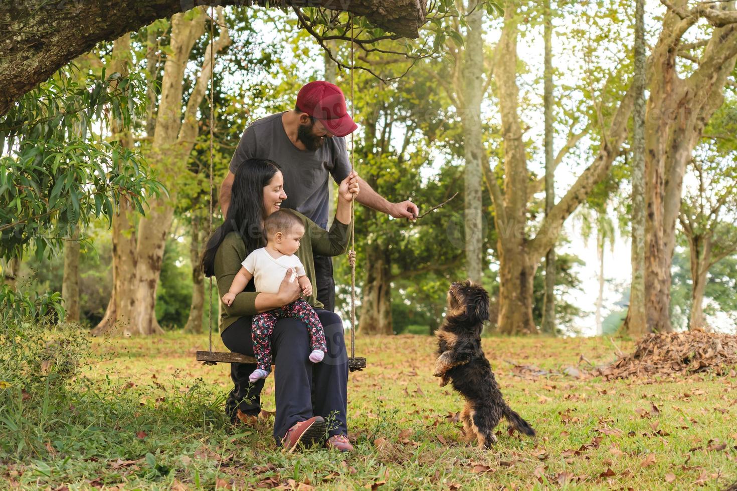 contento famiglia, padre, madre, bambino ragazza e cucciolo giocando nel il parco. foto