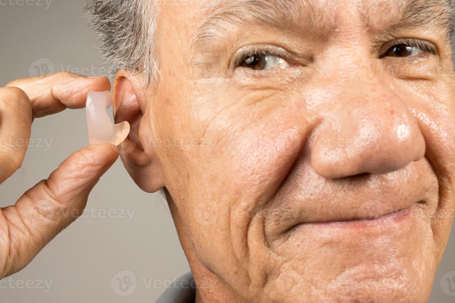 più vecchio uomo utilizzando costume fatto silicone tappi per le orecchie per udito protezione foto