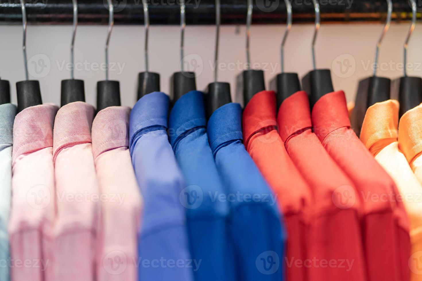 Close up multi camicie colorate su grucce foto