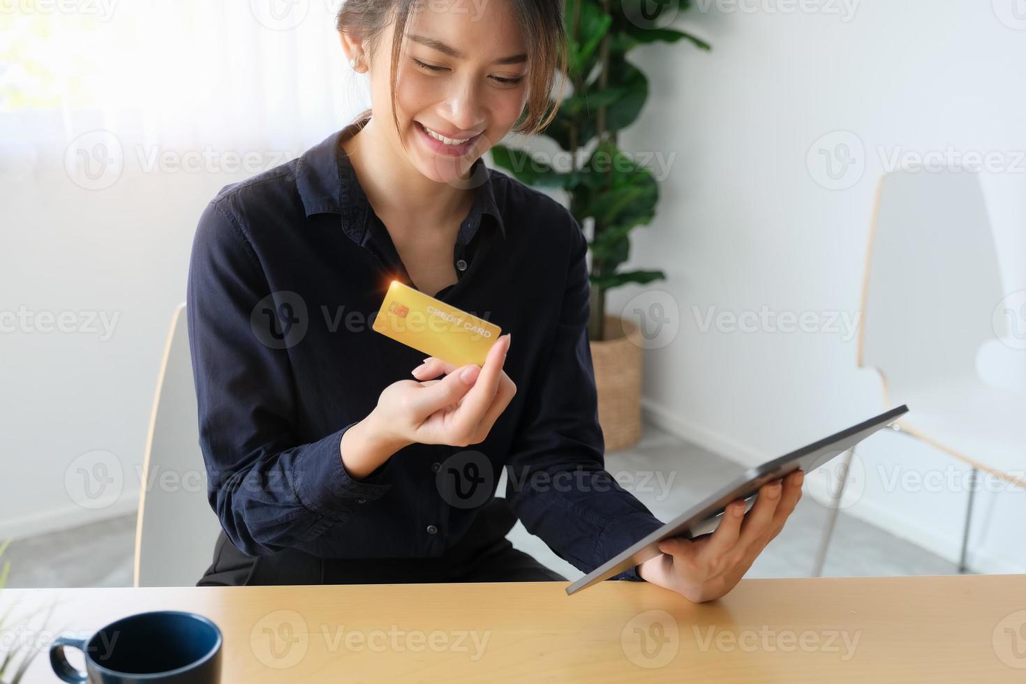 donna che guarda una carta di credito e che tiene un tablet foto