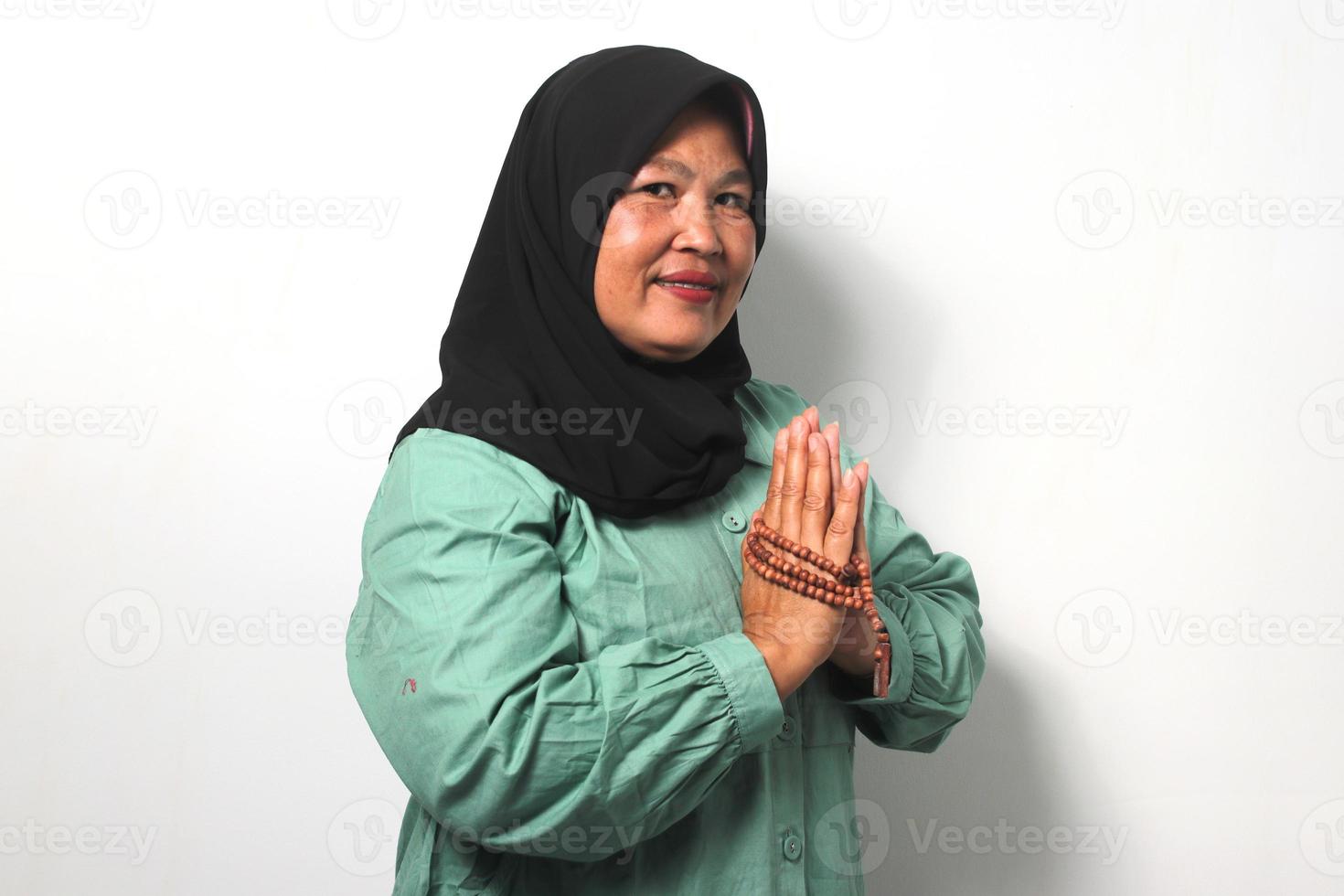 sorridente mezzo anziano asiatico donne indossare hijab Esprimere a gesti eid mubarak al di sopra di bianca sfondo. foto