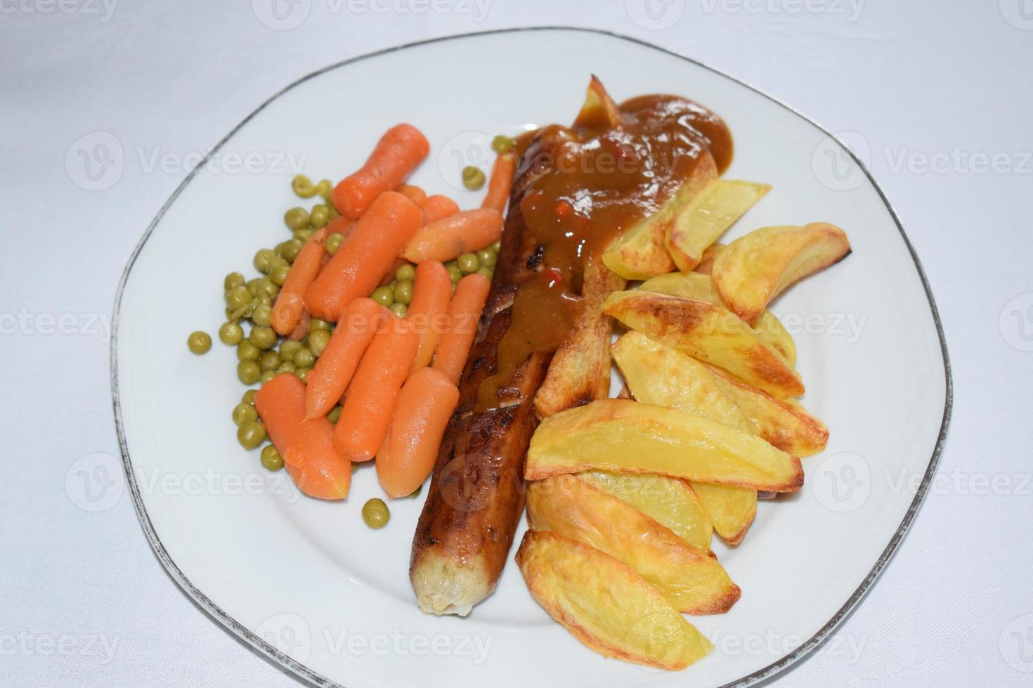 currywurst con patatine fritte, carote e piselli foto