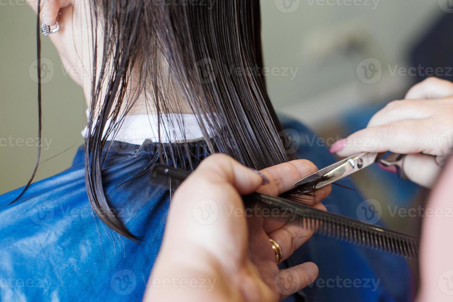 taglio di capelli nel un' bellezza professionale salone. parrucchiere mani taglio brunetta capelli vicino foto