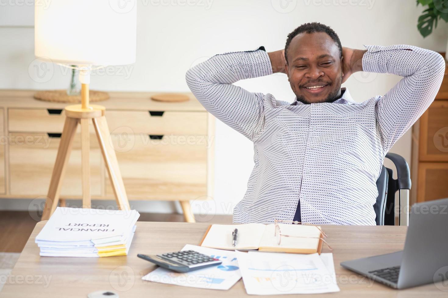 africano americano uomo d'affari sorridente rilassato e attraversato braccia dopo analisi e ricerca a casa ufficio foto